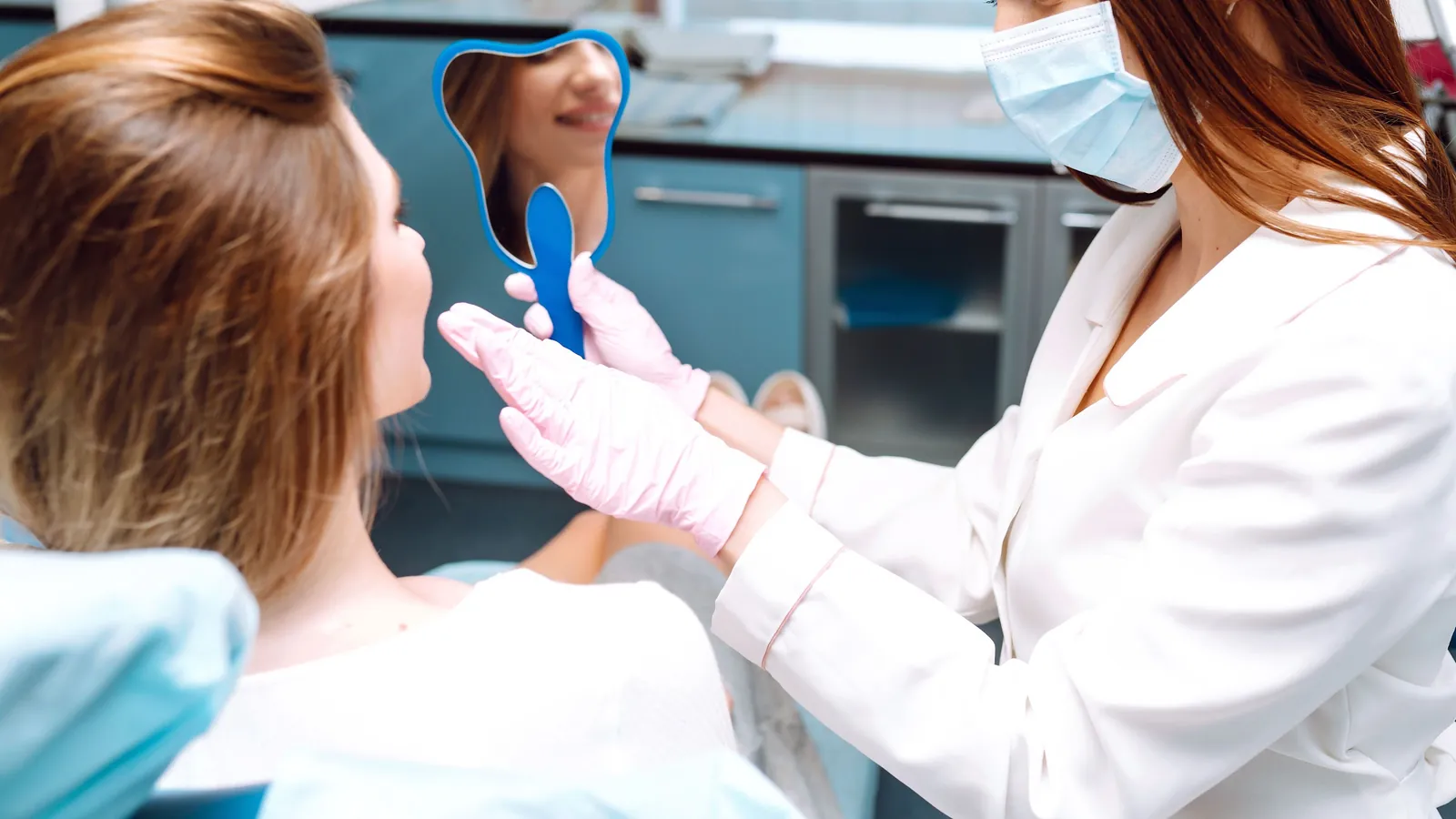 A patient checking her smile in a hand mirror after a checkup