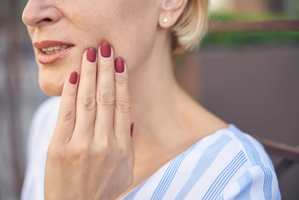 A woman holding her jaw in discomfort