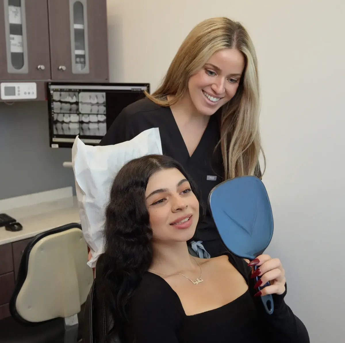 A Solace Dentistry team member with a patient holding a hand mirror