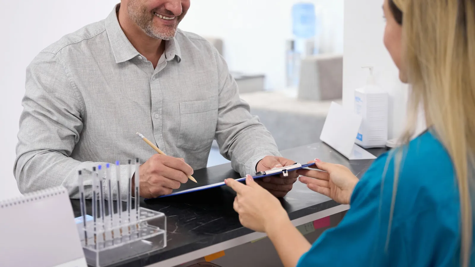 A patient at the front desk speaking with a team member